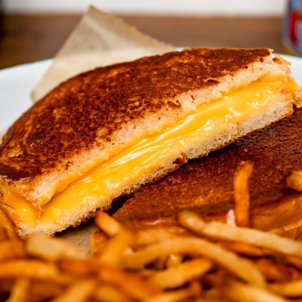 Golden grilled cheese sandwich with melted cheese and a side of crispy french fries.