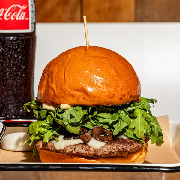 BuffBurger's mushroom and Swiss burger with arugula, served with a Coca-Cola bottle.
